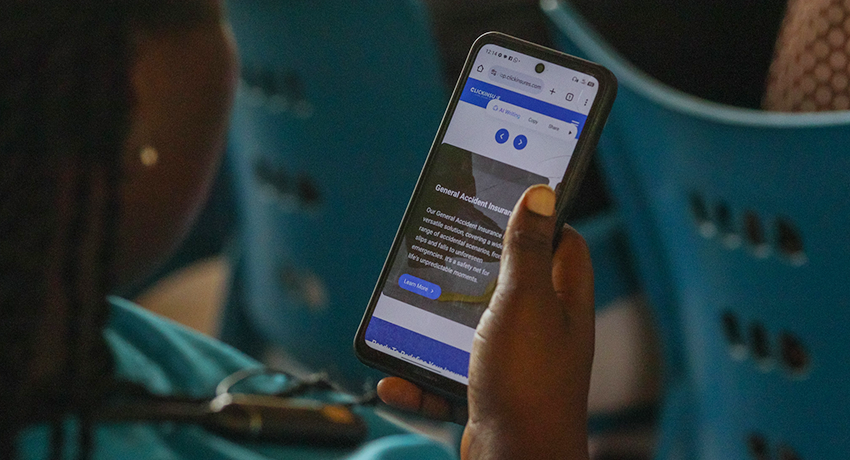 A participant engages in practical digital microinsurance training using a mobile phone.